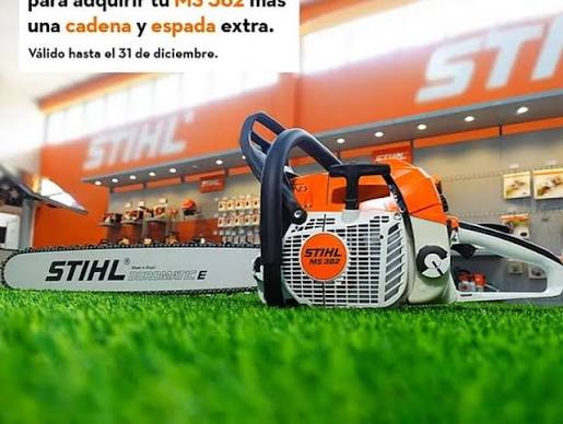 Motosierra Stihl MS 382 sobre césped con tienda Stihl de fondo